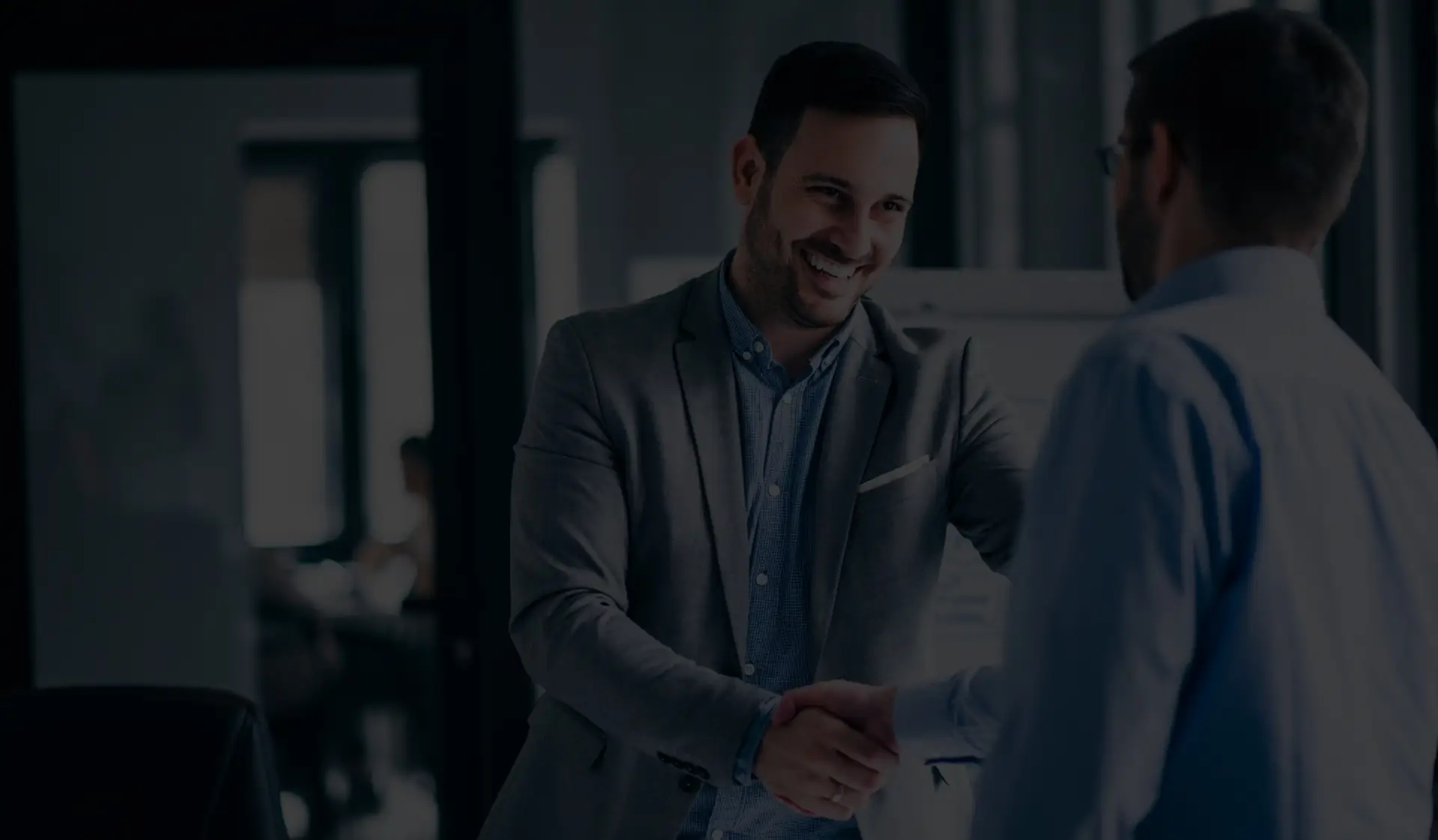 resized two smiling businessmen shaking hands while standing office